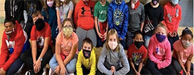 A group of children sitting with masks on.