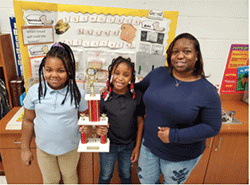 Two kids and a woman proudly displaying a trophy